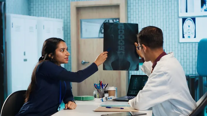 A doctor and patient reviewing a spine X-ray in the clinic