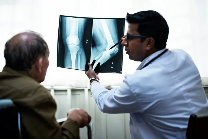 A doctor explaining a knee X-ray to an older patient