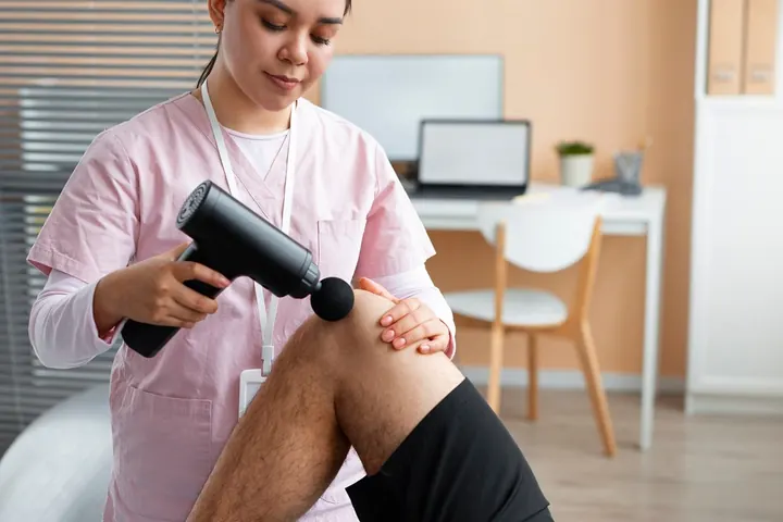 A clinician working on a patient’s knee during rehabilitation